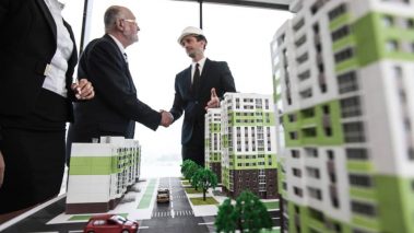 Business people standing near houses models Housing Market: Sales Dropped but Average Price Climbed 27.7%
