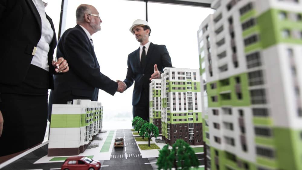 Business people standing near houses models Housing Market: Sales Dropped but Average Price Climbed 27.7%