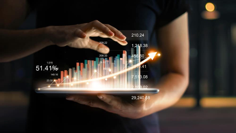 Businessman holding tablet and showing a growing virtual hologram of statistics graph and chart with arrow up on dark background. Stock market. Business growth planning and strategy concept Air Canada (TSX:AC) and Cineplex (TSX:CGX) Could Surge in Summer