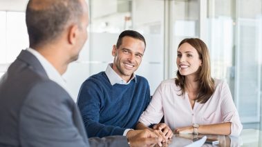 Mature financial advisor showing report to young couple for their investment 2 Beginner Stocks Under Pressure to Buy and Hold